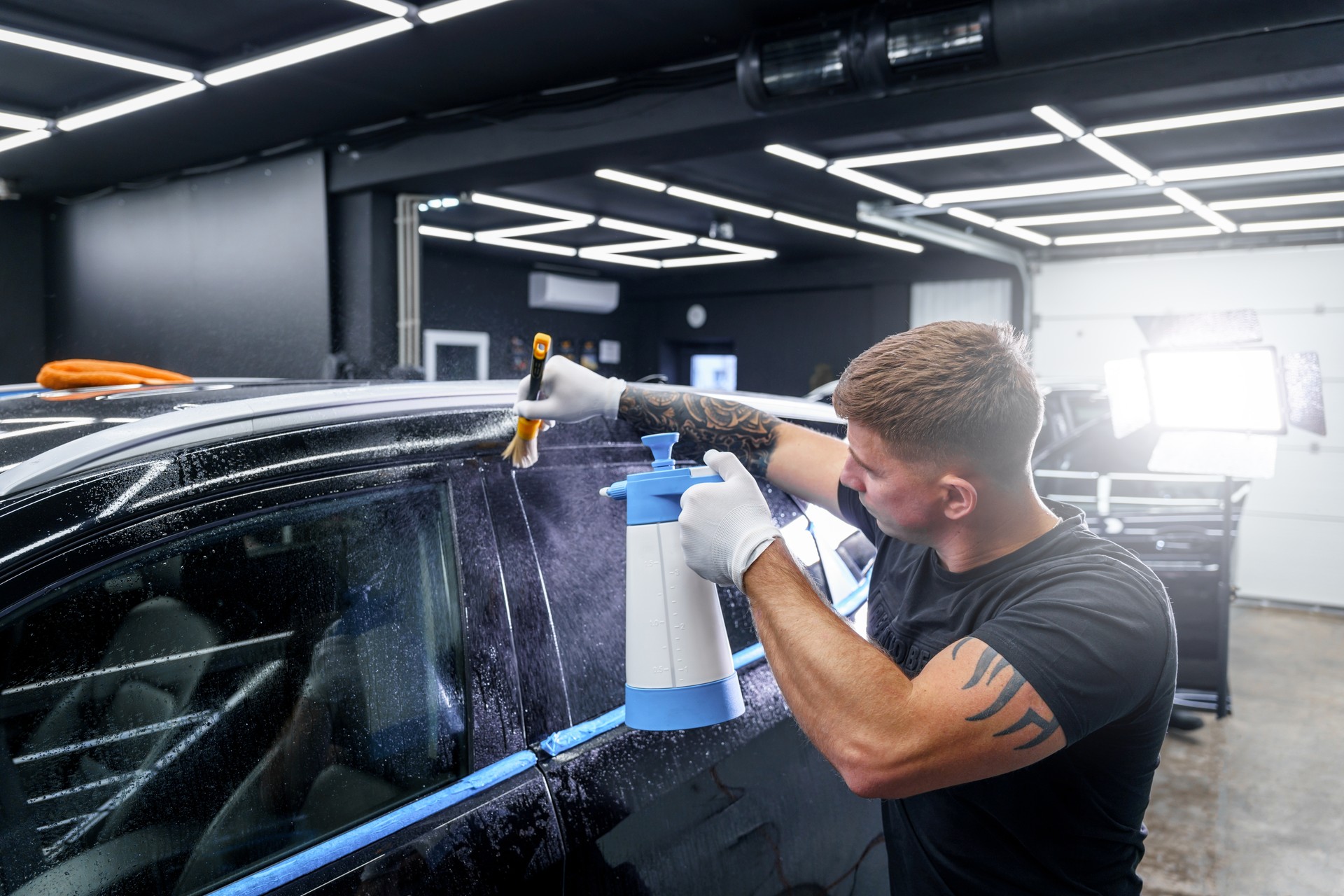 Sticker of a protective film on the headlight of a car in a car detailing studio